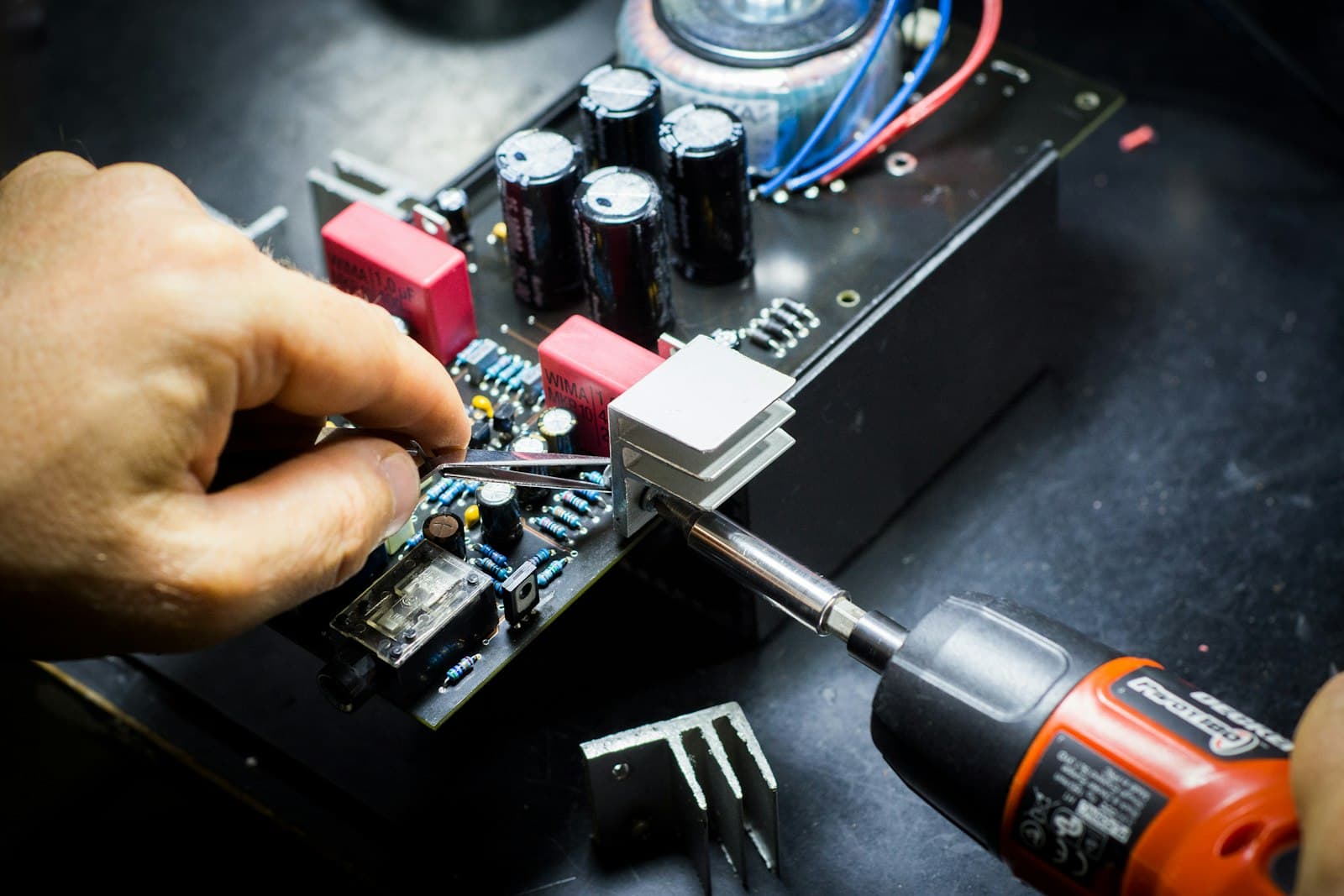 Gros plan sur des mains réparant un circuit électronique avec un tournevis